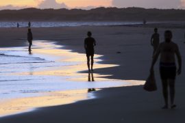 People walk on Shela beach in Lamu, an island in the Indian Ocean off the northern coast of Kenya