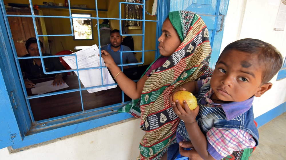 A woman carrying her son arrives to check her name on the draft list of the National Register of Citizens at an NRC centre in Chandamari village