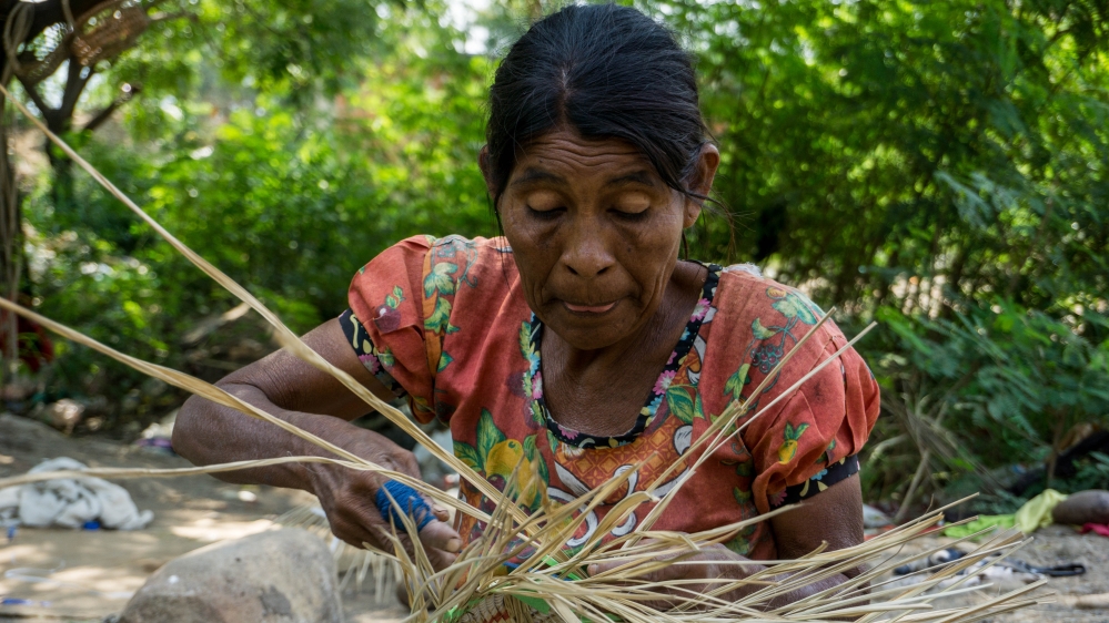 An elder Yukpa woman is braiding a basket that are sold to help support the community [Bram Ebus/Al Jazeera]