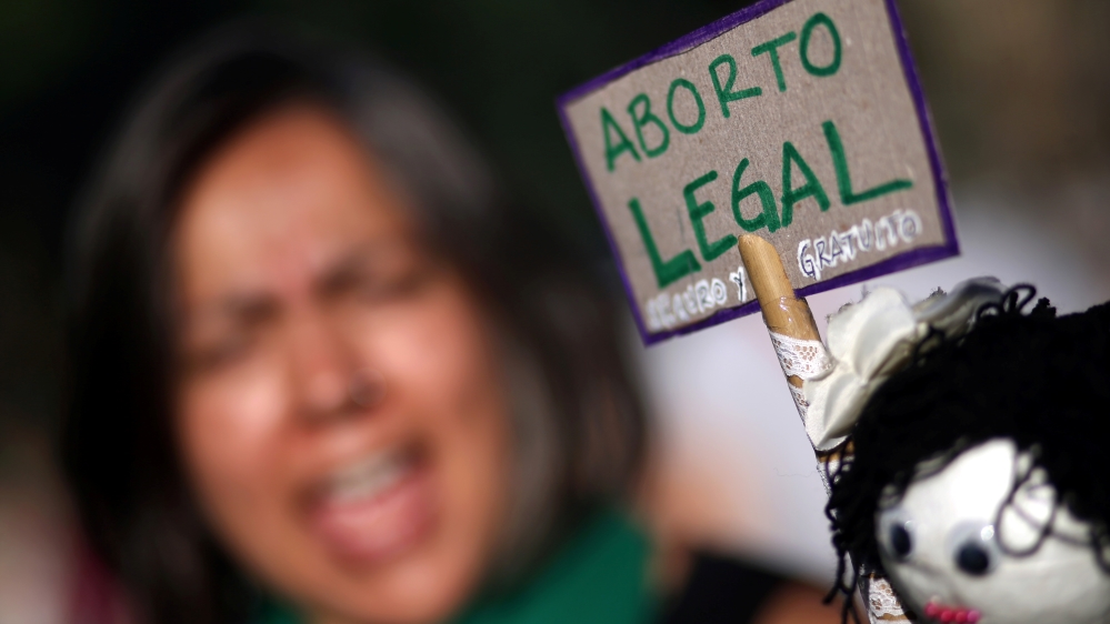 A woman shouts slogans next to a sign that reads 'Legal abortion' during a demonstration on International Women's Day in Buenos Aires [Marcos Brindicci/Reuters]