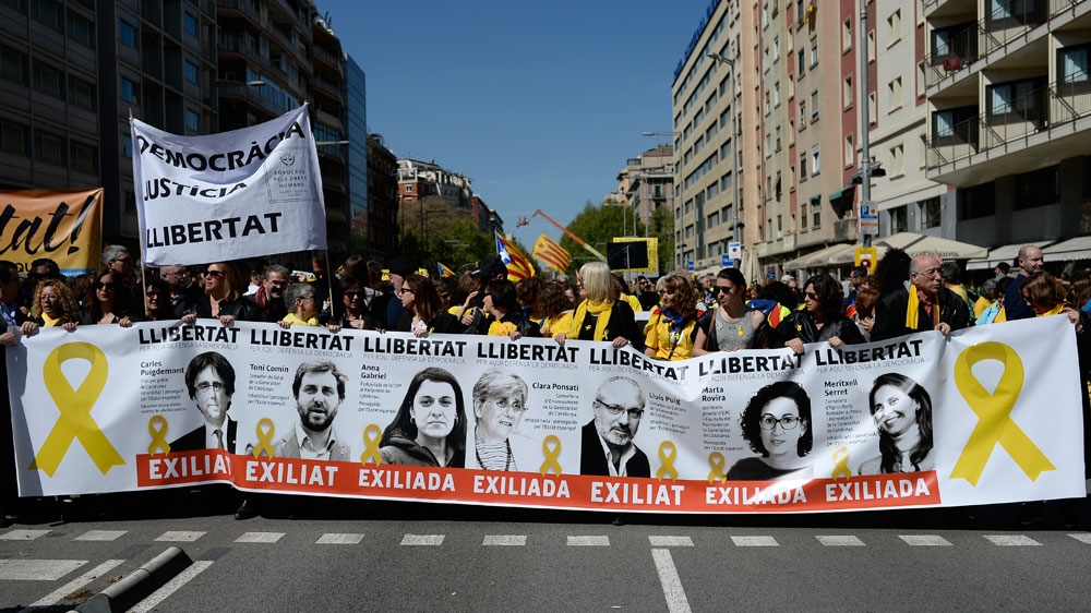 People hold a banner depicting portraits of exiled Catalan politicians during a pro-independence demonstration in Barcelona on April 15 [Josep Lago/AFP]