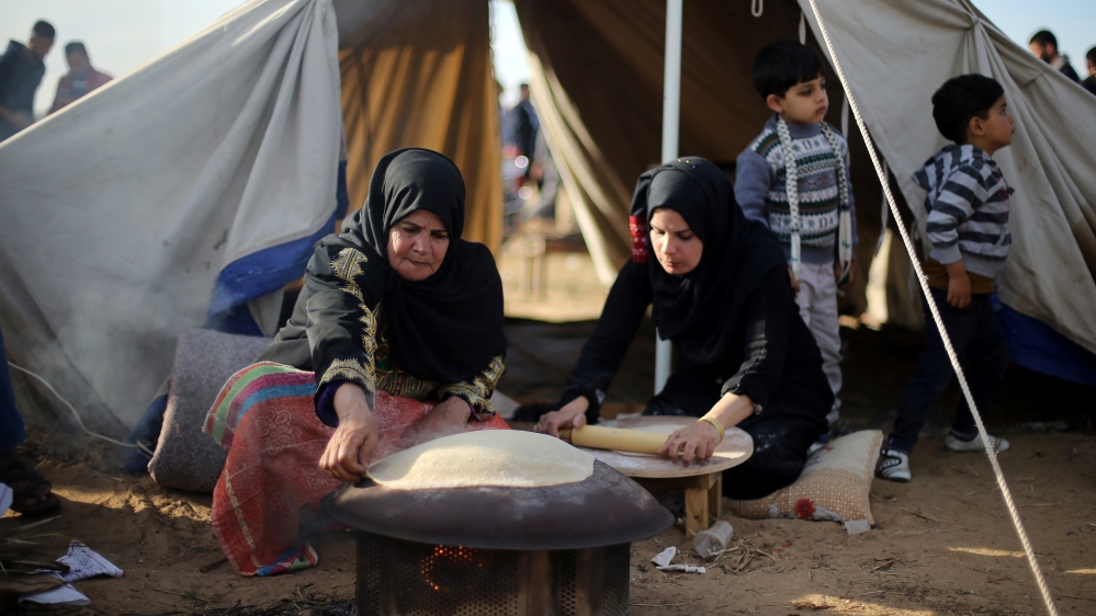 Palestinian women bake bread during a tent city protest at Israel-Gaza border, in the southern Gaza Strip [Ibraheem Abu Mustafa/Reuters]