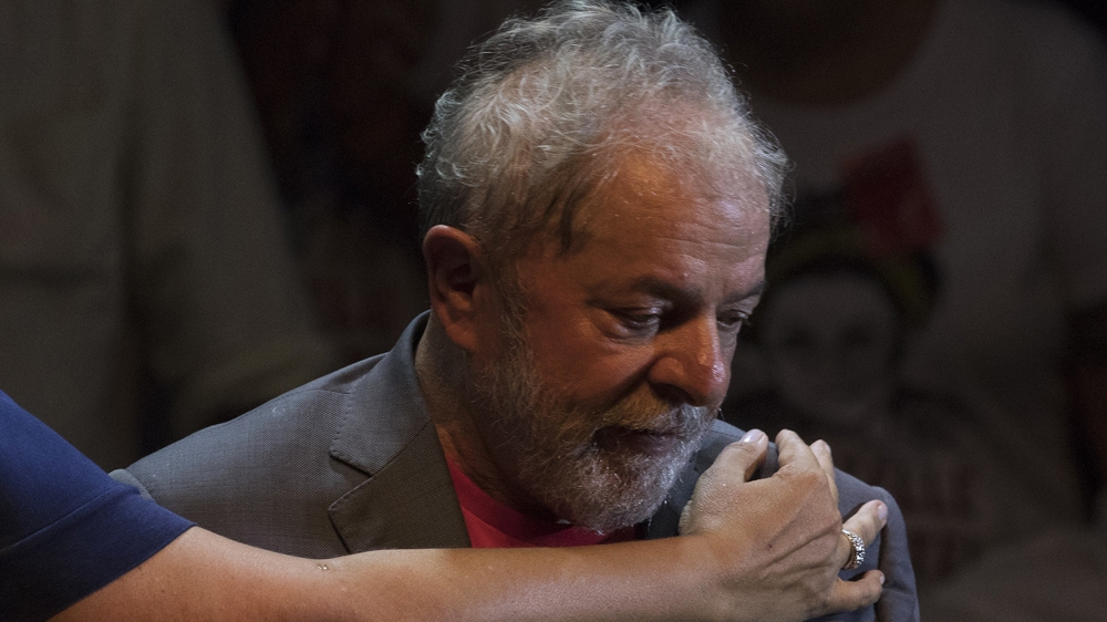 Brazil's former President Luiz Inacio Lula da Silva is embraced during his presidential campaign rally with members of his Workers Party [Leo Correa/AP Photo] 
