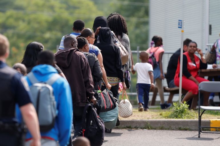 FILE PHOTO: A group of asylum seekers wait to be processed after being escorted from their tent encampment to the Canada Border Services in Lacolle