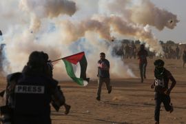 Palestinian demonstrators run from tear gas fired by Israeli troops during a protest marking the 70th anniversary of Nakba, at the Israel-Gaza border in the southern Gaza Strip