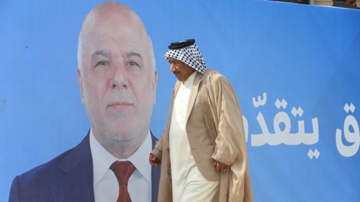 A man walks past a campaign poster of Iraqi Prime Minister Haidar al-Abadi ahead of the parliamentary election, in Najaf