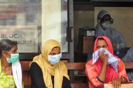People wear masks as they wait outside a casualty ward at a hospital in Kozhikode