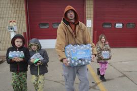 A local family carry bottled water they picked up from a fire station in Flint, Michigan February 7, 2016 [Rebecca Cook/Reuters]