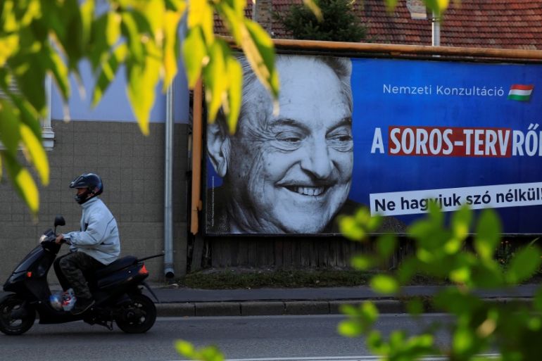 A man rides his moped past a government billboard displaying George Soros in monochrome next to a message urging Hungarians to take part in a national consultation about what it calls a plan by the Hu