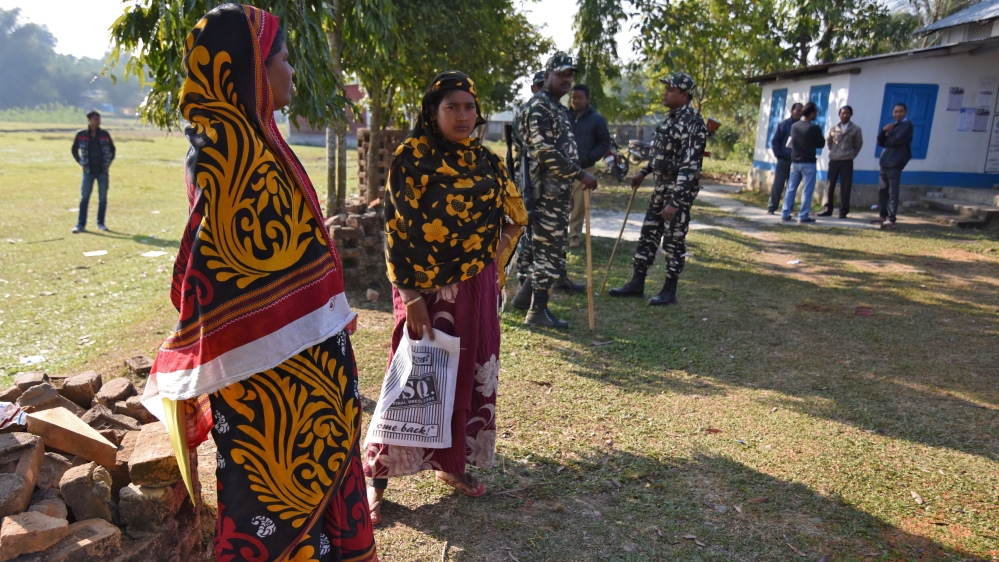 Women stand next to police as they wait to check their names on the draft list of the National Register of Citizens (NRC) [File: Anuwar Hazarika/Reuters]