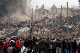 Onlookers watch as bulldozers demolish houses to make way for a new road in the Kibera slum in Nairobi, Kenya