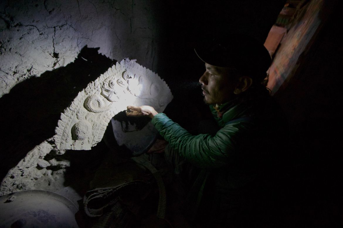 4. Tashi Bista examines ancient armor discarded in a hallway in a monastery built into a cliff in Mustang, Nepal. Tashi, a local Mustang resident, has fought for years to stop the theft of antiquitie
