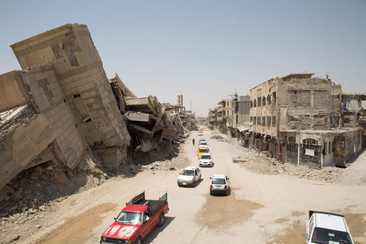 Photo 11 A street in Mosul’s old city. Cars and inhabitants circulate with difficulty in this apocalyptic scenery, as small adjacent streets are not safe yet. Photo: Tom Peyre-Costa/NRC. 03/07/2018 –