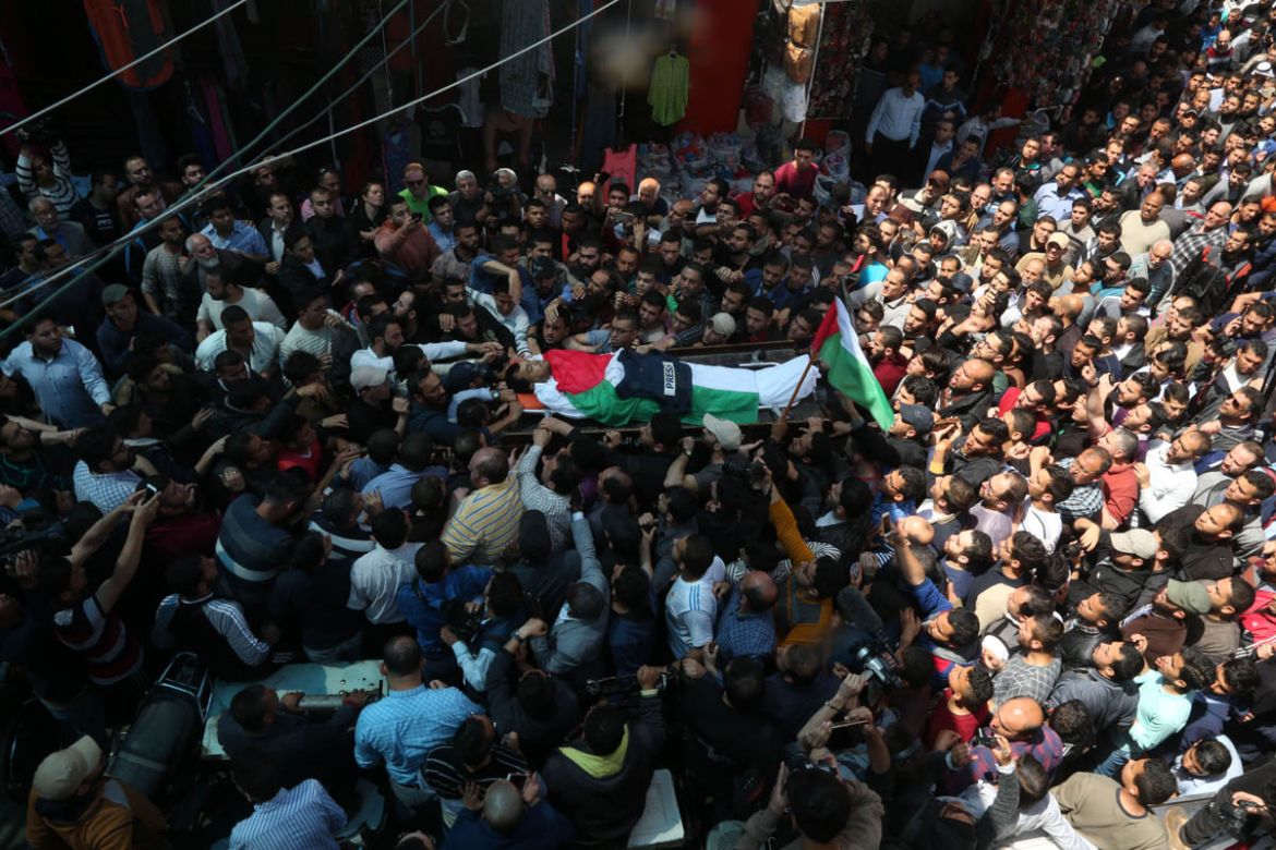 Mourners, together with fellow journalists, carry the body of Palestinian journalist Yasser Murtaja, during his funeral in Gaza City on April 7, 2018. He died from his wounds after being fatally shot