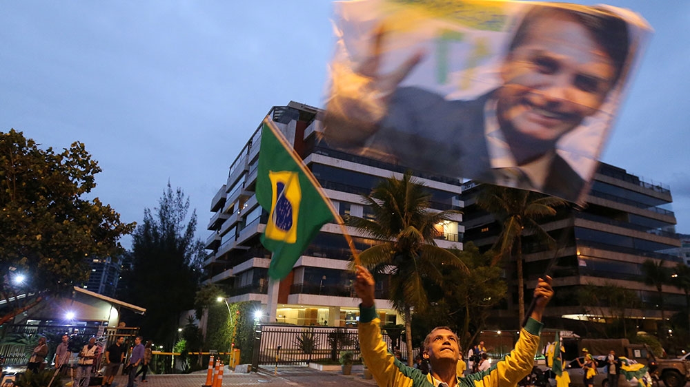 A supporter of Brazilian presidential candidate Jair Bolsonaro is seen in front of Bolsonaro's condominium at Barra da Tijuca neighbourhood in Rio de Janeiro [File: Sergio Moraes/Reuters]