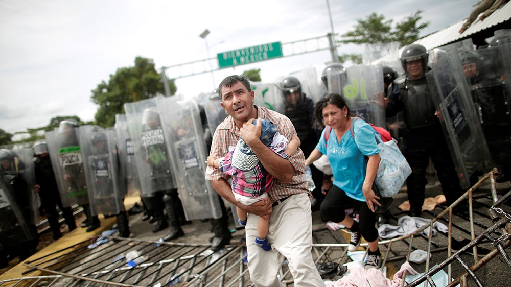 A Honduran migrant protects his child after fellow migrants and refugees, part of a caravan trying to reach the US, stormed a border checkpoint in Guatemala, in Ciudad Hidalgo, Mexico [Ueslei Marcelino/Reuters] 