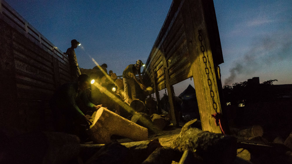 A truck full of wood is unloaded at a brick kiln on the periphery of Phnom Penh [Thomas Cristofoletti/Royal Holloway]