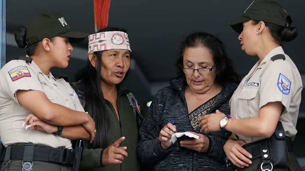 An Indigenous woman from the Amazon region, talks to a couple of police officer during a peaceful occupation of the entrance to the headquarters of the state petroleum enterprise PetroEcuador [Dolores Ochoa/AP Photo]
