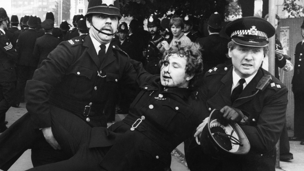 August 1977: An injured policeman is carried from Lewisham riot by colleagues [Getty Images]