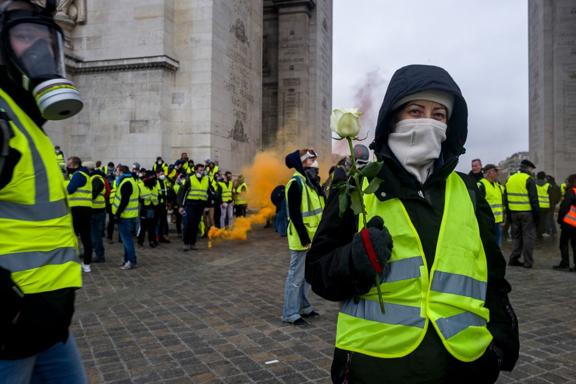 A i`Gillet Jaunei^ demonstrator holds a flower as a symbol of a peaceful protest under the world famous i`Arc de Triopmhei^ during a demonstration on a street near the Champs ElysE`es called for by th