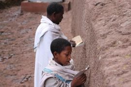 A man and young boy reciting prayers outside the walls of Bet Maryam, one of the larger churches dedicated to the Virgin Mary. Tradition has it that this was the first church excavated at Lalibela, an