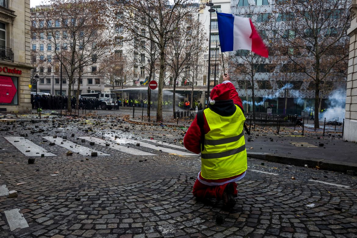 A protester holding a French flag and dressed as Santa Claus shouts slogans to police forces during a demonstration near the Champs ElysE`es called for by the i`Gilets Jaunesi^ movement on December 01