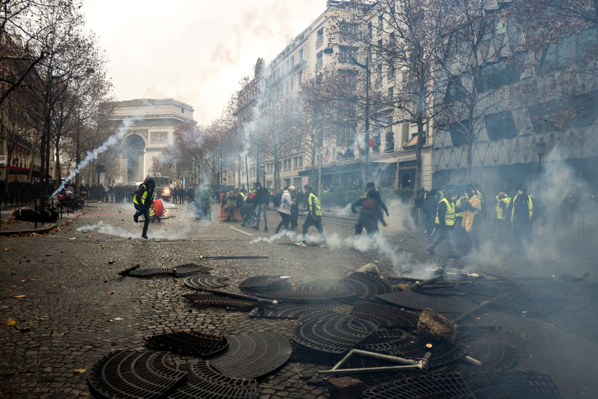 A group of protesters run after police force shot tear gas towards them during a protest on the adjacent streets to the Champs ElysE`es called for by the i`Gilets Jaunesi^ movement on December 01, 20