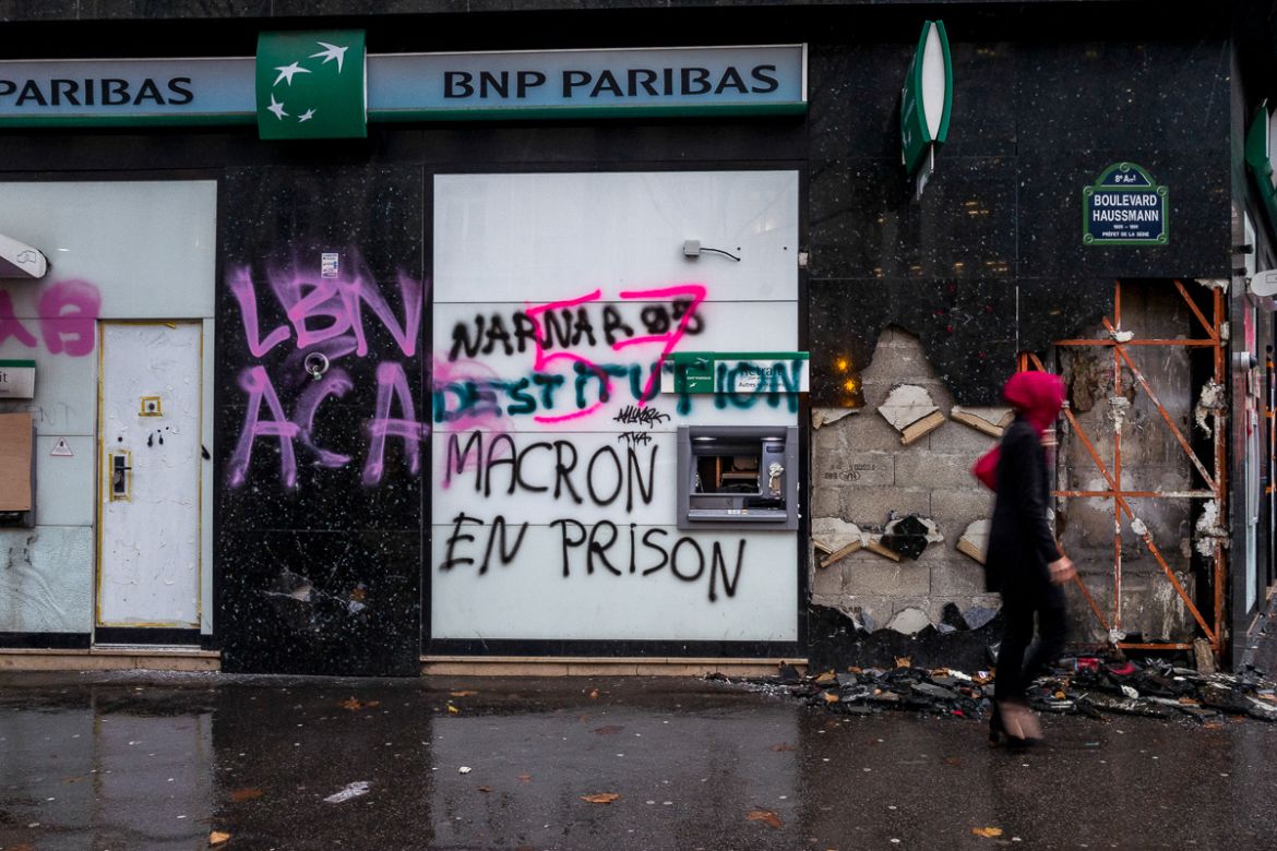 A woman walks by a BNP Paribas branch where messages against French President Macron were written during last Saturdayi´s protests on December 03, 2018 in Paris, France. After the violent protest of l