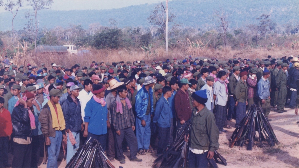 Khmer Rouge cadres stand in front of piles of weapons during a reintegration ceremony in Anlong Veng in early 1999 [Courtesy Documentation Center of Cambodia/Al Jazeera]