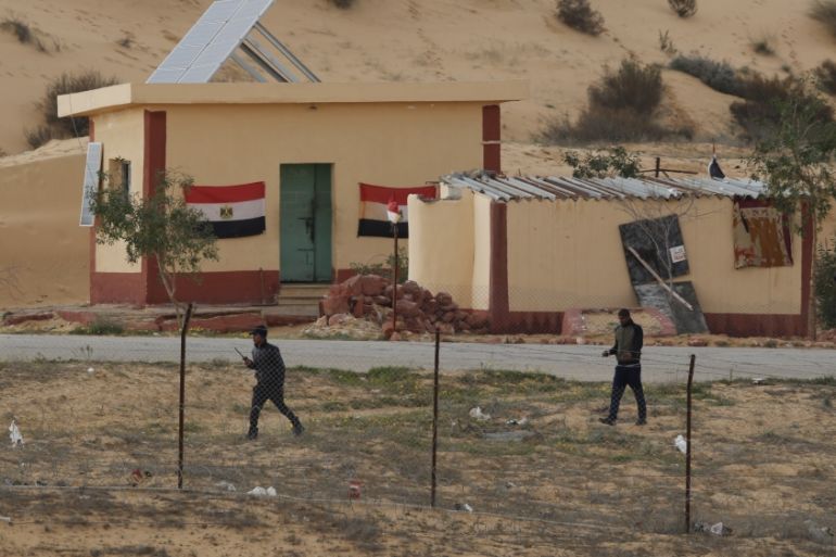 Egyptian policemen walk next to a border post, as seen from the Israeli side of the border with Egypt''s Sinai peninsula