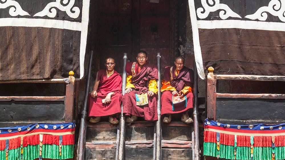 Monks resting on the wooden steps of Rinchenling, which is believed to be the last of the 108 monasteries built by the legendary translator Rinchen Zangpo during the second renaissance of Buddhism in Tibet [Neelima Vallangi/Al Jazeera]