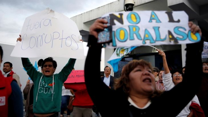 People hold up signs during a protest outside La Aurora International Airport in support of Yilen Osorio, a member of the UN anti-corruption commission (CICIG) detained upon his arrival to the airport