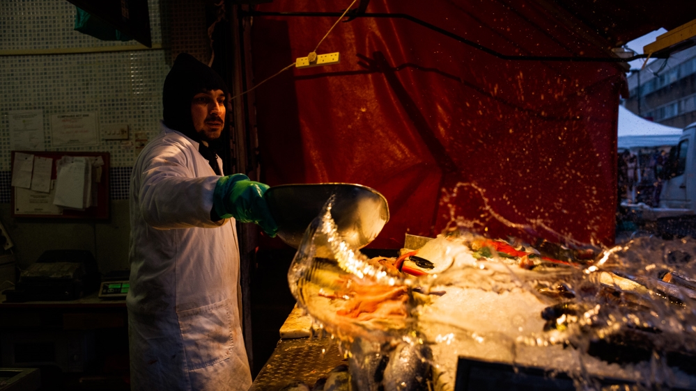 An Afghan man from Kabul works at his fish stall on an early Saturday morning [Jose Sarmento Matos/Al Jazeera]