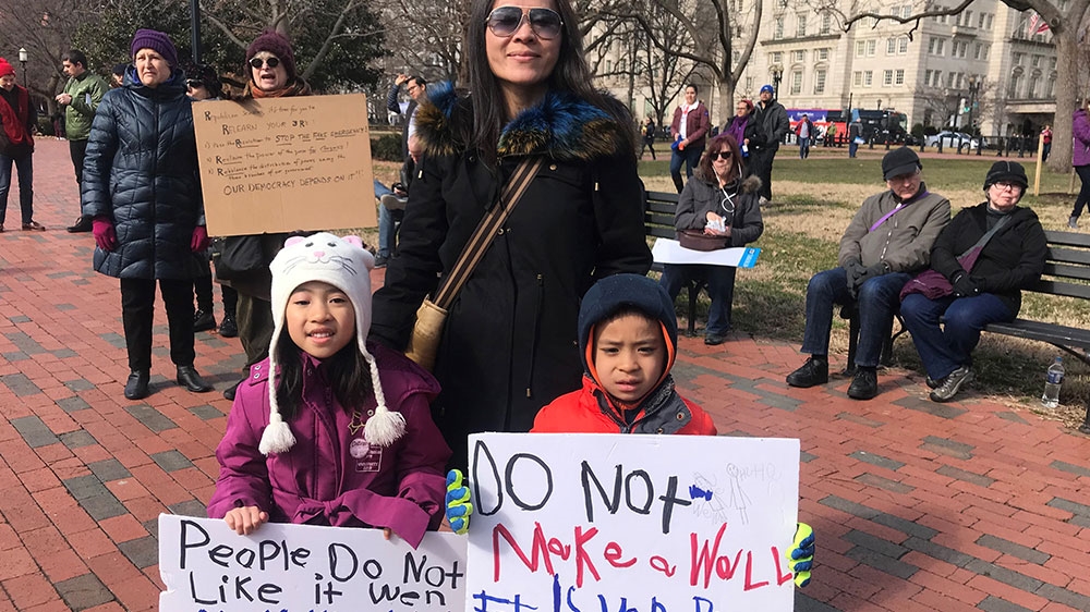 Angelina Huynh joins a rally in Washington, DC, against Trump's national emergency deceleration with her two children on February 18, 2019. [Ola Salem/Al Jazeera]