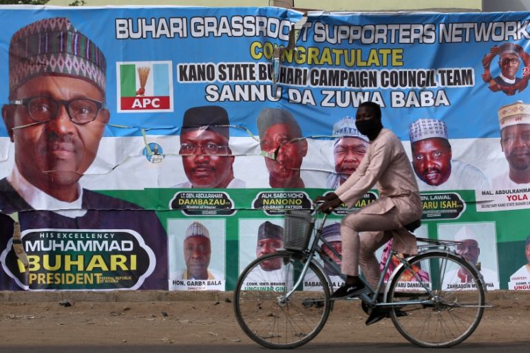 A cyclist drives pasts a campaign poster for President Muhammadu Buhari in a street after the postponement of the presidential election in Kano