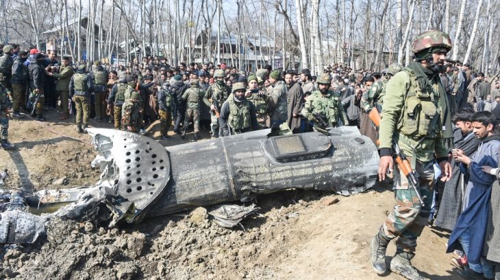 Indian soldiers and Kashmiri onlookers stand near the remains of an Indian Air Force aircraft after it crashed in Budgam district, some 30 kms from Srinagar on February 27, 2019.