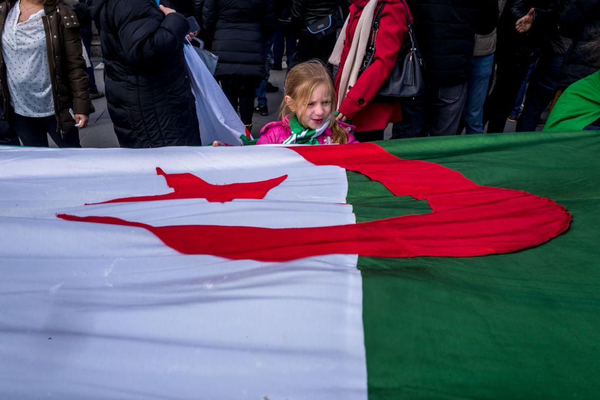 An young girl holds onto an Algerian flag during a demonstration against Algerian President Abdelaziz Bouteflika seeking a fifth term in Place de la RE`publique in Paris, France. Photo by Omar Havana