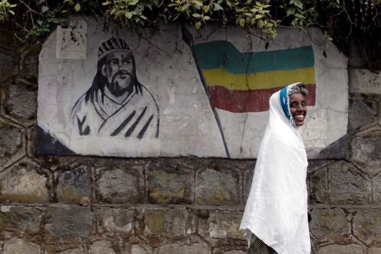 A traditionally-dressed Ethiopian woman walks past a mural depicting Ethiopia''s Emperor Tewodros II in Addis Ababa, Ethiopia