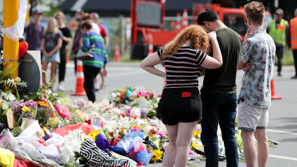 People pay their respects by placing flowers for the victims in Christchurch on Saturday [Michael Bradley/AFP]