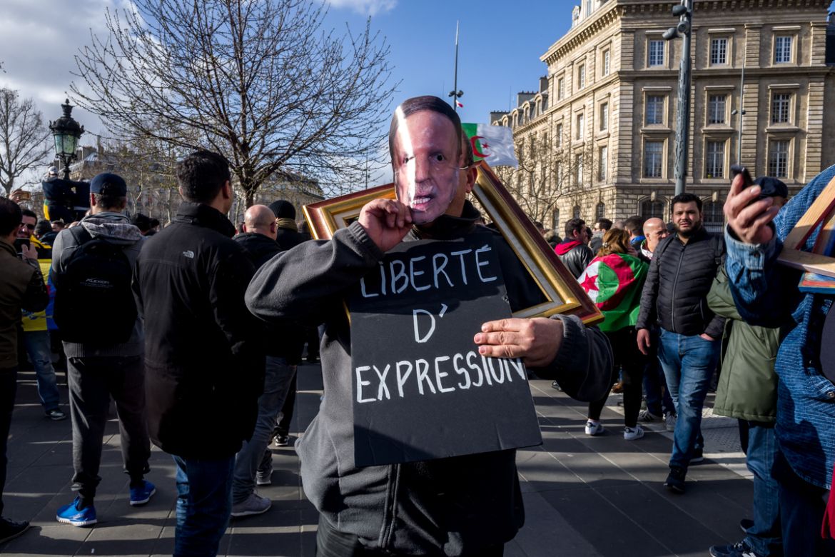 An Algerian protester wearing a mask of Algerian President Abdelaziz Bouteflika and a sign decrying restrictions against freedom of expression in Algeria during a demonstration against the president s