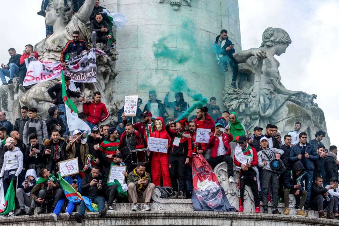 A group of Algerian protesters shout slogans holding flares on top of the Monument ‡ la RE`publique during a demonstration against Algerian President Abdelaziz Bouteflika in Place de la RE`publique in