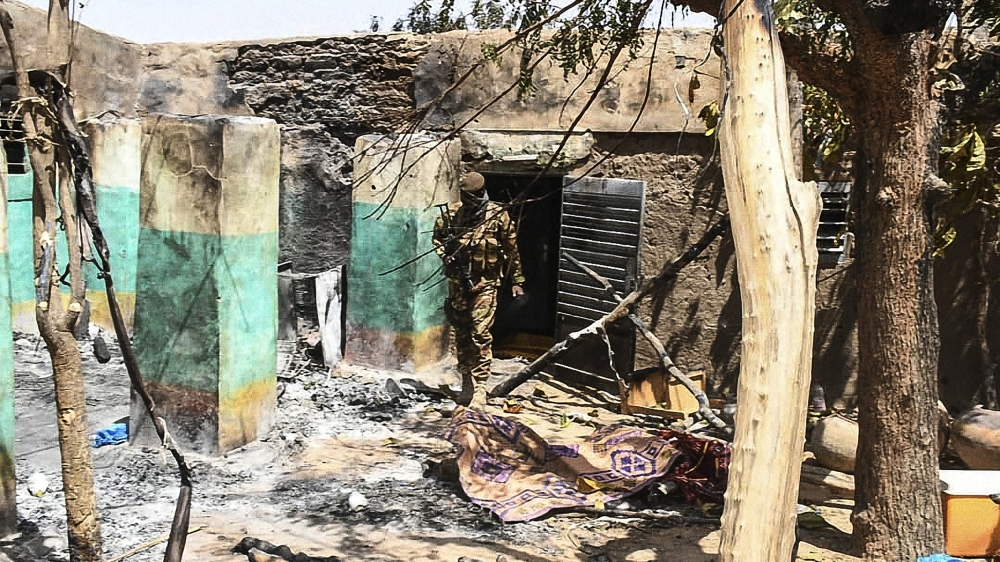 A soldier walking among rubble of a house destroyed during an attack on March 23, on the village of Ogassogou, near Mopti, where 160 Fulani people, including women and children, were killed [Malian Presidency/Handout via AFP]
