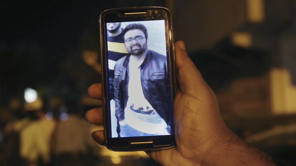 A relative shows the picture of Areeb Ahmed on his mobile phone outside his home in Karachi, Pakistan [Fareed Khan/AP]