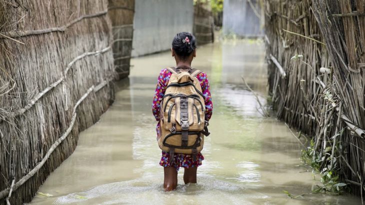 A child wades through water on her way to school in Kurigram district of northern Bangladesh during floods in August 2016 [UNICEF]