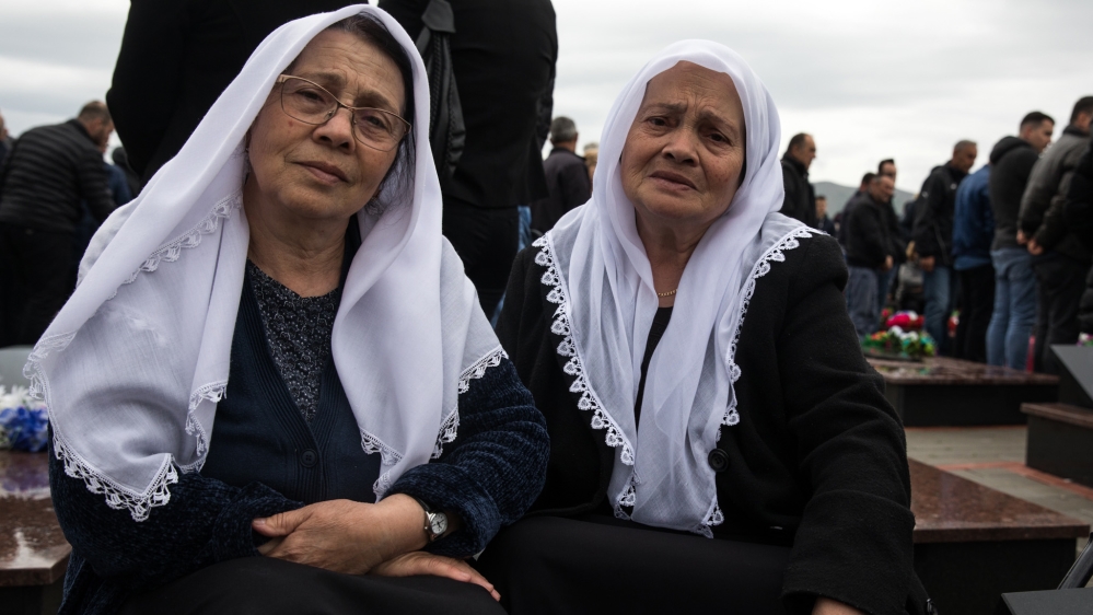 Sisters Xufe Hoxha and Hate Jasiqi sit next to the grave of Xufe’s son who was killed on April 27, 1999 [Valerie Plesch/Al Jazeera]