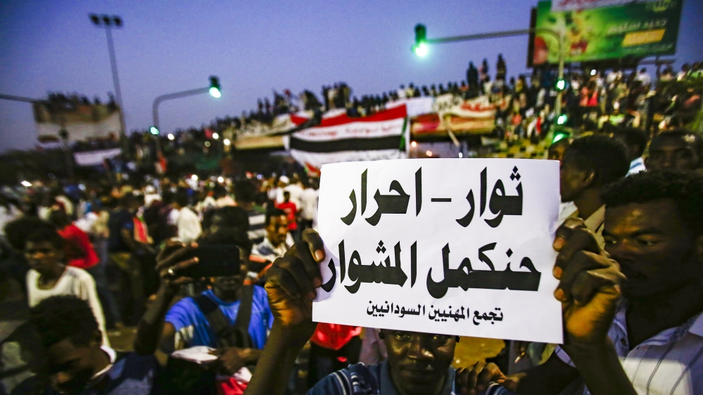 A Sudanese protester holds up a sign reading in Arabic 
