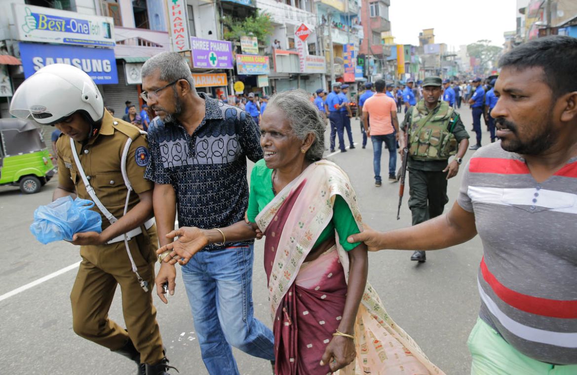 Sri Lankan elderly woman is helped near St. Anthony''s Shrine after a blast in Colombo, Sri Lanka, Sunday, April 21, 2019. Dozens of people were killed and hundreds wounded in near simultaneous blasts