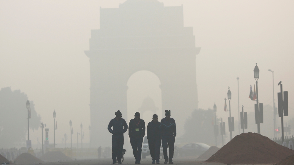 Men walk in front of the India Gate shrouded in smog in New Delhi