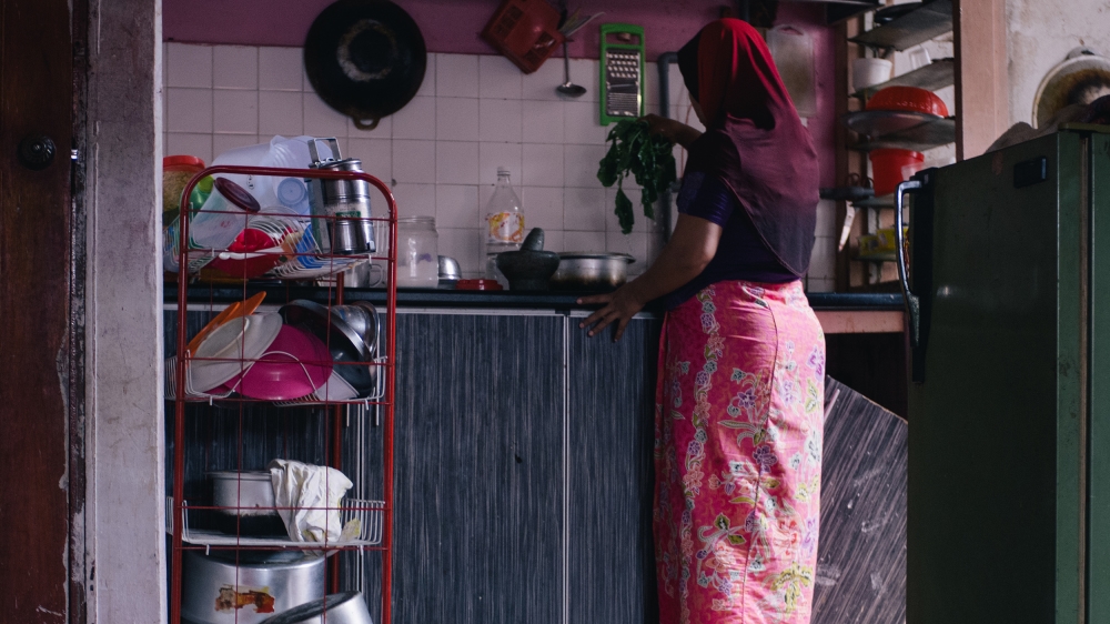 A Rohingya woman cooks in her apartment in Kuala Lumpur [Kaamil Ahmed/Al Jazeera]