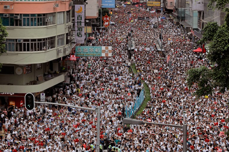 Protesters march along a downtown street against the proposed amendments to an extradition law in Hong Kong Sunday, June 9, 2019. A sea of protesters is marching through central Hong Kong in a major
